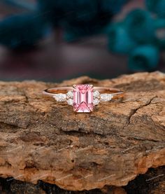 a pink tourmaline and diamond ring sitting on top of a rock