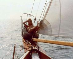 a man sitting on top of a boat in the ocean