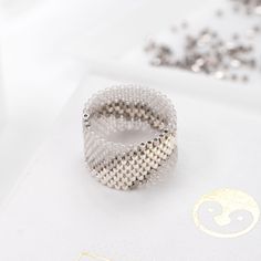 a silver ring sitting on top of a white box next to some beads and confetti