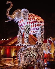 an elephant statue made out of glass in front of a tent with lights on it