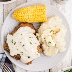 a white plate topped with meat, mashed potatoes and corn on the cob