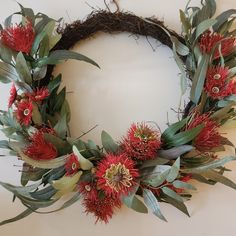 a wreath with red flowers and green leaves