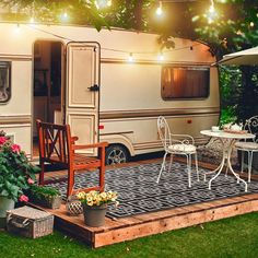 an rv is parked in the backyard with chairs and tables