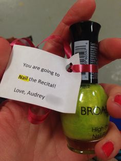 a person holding a bottle of nail polish in their hand with a note attached to it