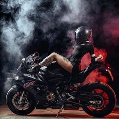 a woman sitting on top of a motorcycle with steam coming out of the back ground