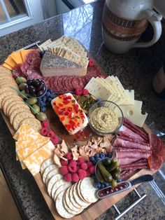 an assortment of cheeses, crackers, and meats on a cutting board