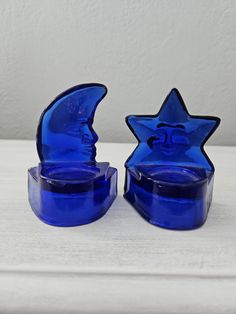 two blue glass candlesticks sitting on top of a white table next to each other