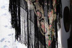 a black shawl hanging from the side of a window with floral designs on it