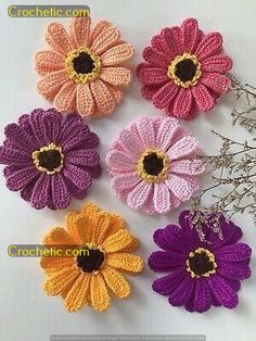 crocheted flowers are arranged on a white table top with the words crochet com written below them