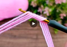 a video demonstrating how to tie a pink rope with a black handled crochet hook