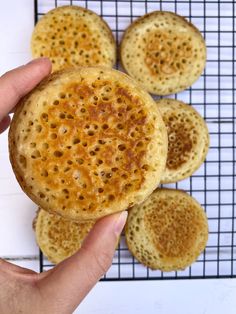 a hand holding a piece of bread on top of a cooling rack