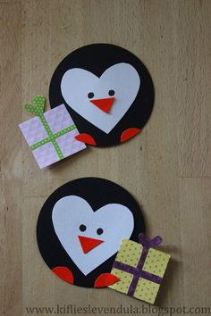 two penguins with gifts on their backs made out of paper and cardboard, sitting on a wooden surface