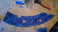 the tools are laying on the floor next to the blue mosaic tiles and some wires