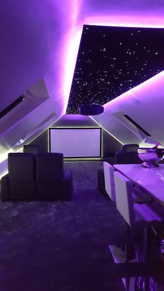 a room that has some couches and chairs in it with purple lighting on the ceiling