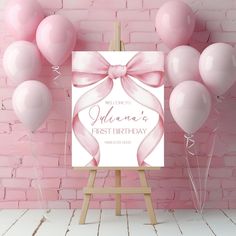 a pink birthday card with balloons on an easel in front of a brick wall