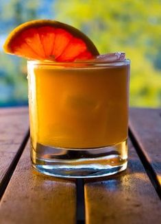 an orange drink sitting on top of a wooden table