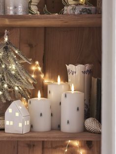 lit candles are sitting on a shelf in front of a christmas tree and other decorations