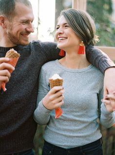 a man and woman holding ice cream cones in their hands, smiling at each other