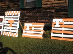 three wooden signs sitting in the grass near a building