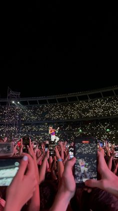 people are taking pictures with their cell phones at an outdoor music concert in the dark