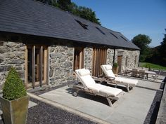 two chaise lounge chairs sitting on a patio next to a stone building