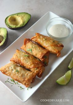 some food is sitting on a white plate next to an avocado and sour cream