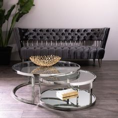 a glass table sitting on top of a hard wood floor next to a black couch