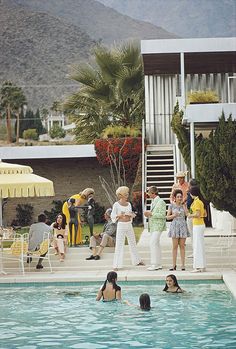 some people are in the pool and one person is holding a baby while others stand around