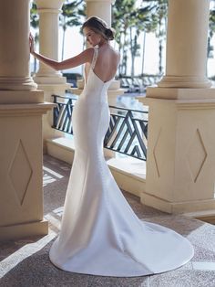 a woman in a white wedding dress standing by pillars