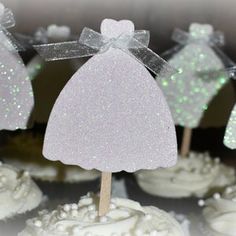 cupcakes decorated with white frosting and glitter bows are arranged on top of each other