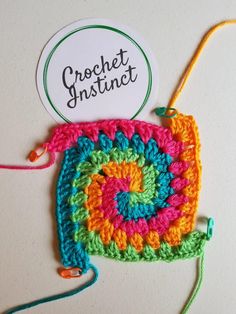 there is a crocheted square with a name tag attached to it and some yarn