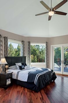 a bedroom with hardwood floors and large windows