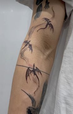 a man's arm with tattoos on it and two birds flying over the water