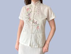 1970's Vintage Chinese Hand Embroidered Bird & Floral Blouse Shirt Great vintage blouse with embroidered details and frog toggles/ closures up the front. The make is daffodil, made in China. In good used condition, some faint dye bleeding on the back from the embroidery- see last pic. Material is 80% polyester, 20% cotton. Labelled as a medium, it comes up small and would be approximately a uk 10 which I'd say is more of a modern day small. Measures 39 inches at the bust, 25 inches long. Vintage Collared Shirt With Floral Embroidery, Vintage Embroidered Long Sleeve Blouse, Vintage Embroidered V-neck Top, Vintage Embroidered Beige Blouse, Folk Style Blouse With Embroidered V-neck, Embroidered Bird, Floral Blouse, Blouse Vintage, 1970s