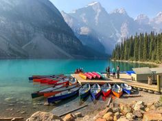 several canoes are docked at the shore of a mountain lake