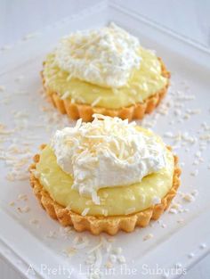 two cupcakes topped with whipped cream and sprinkles on a white plate