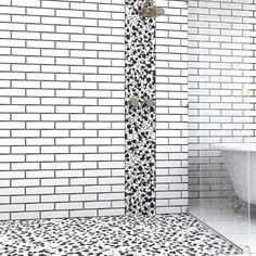 a bathroom with black and white tiles on the floor, shower head and bathtub