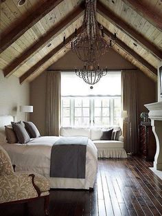 a bedroom with wood flooring and a chandelier hanging from the vaulted ceiling