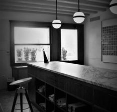 an empty room with a long counter and two stools in front of the window