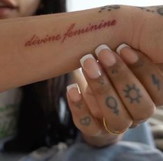 a woman holding her arm with the word divine feminine written on it in red ink