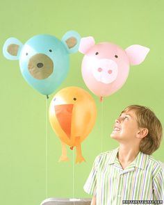 a man is looking up at three balloons in the shape of bears and pigs