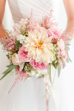 a bride holding a bouquet of pink and white flowers