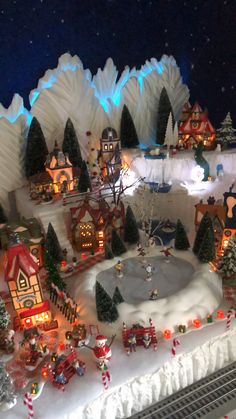 a christmas village with lots of lights and decorations on it's display wall,