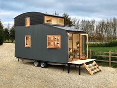 a tiny house on wheels is parked in the gravel