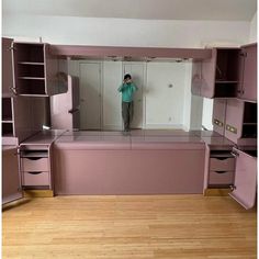 a person taking a selfie in front of an empty room with cabinets and drawers