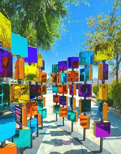 many colorful chairs are lined up on the sidewalk