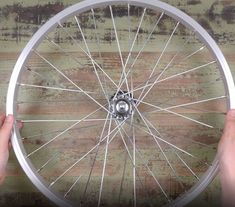 two hands hold the spokes of a bicycle wheel