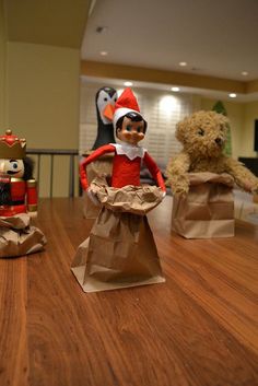 two stuffed animals sitting next to each other on top of a wooden table with paper bags