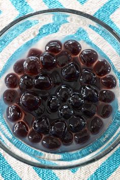 a glass bowl filled with raisins on top of a blue and white towel