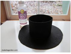 a black hat sitting on top of a table next to a window